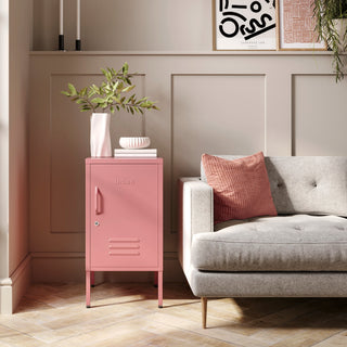 The Camden flamingo pink metal storage locker as a side table next to a sofa