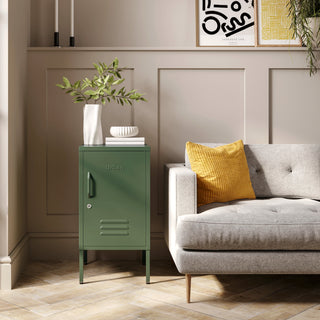 The Camden forest green metal storage locker as a side table next to a sofa