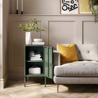 The Camden forest green metal storage locker open as a side table next to a sofa