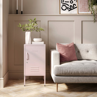 The Camden light pink metal storage locker as a side table next to a sofa