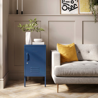 The Camden navy blue metal storage locker as a side table next to a sofa