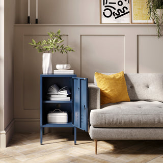 The Camden navy blue metal storage locker open as a side table next to a sofa