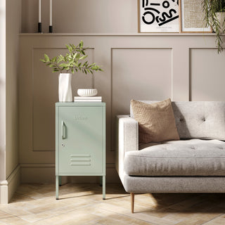 The Camden sage green metal storage locker as a side table next to a sofa