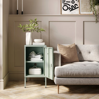 The Camden sage green metal storage locker open as a side table next to a sofa