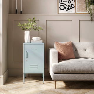 The Camden sky blue metal storage locker as a side table next to a sofa