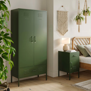 Metal, tall, double-door and single-drawer storage locker and a metal side table locker with one drawer and one door, both in forest green in a room next to a bed