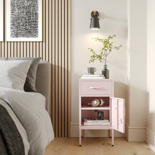 Metal side table locker in light pink with one drawer and one door open showing books, in a room next to a bed