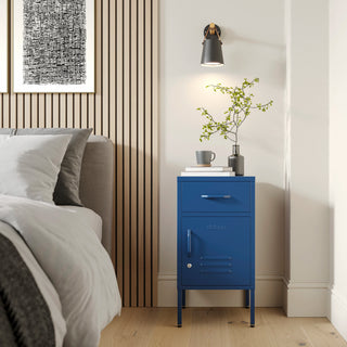 Metal side table locker in navy blue with one drawer and one door, in a room next to a bed