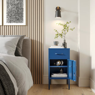 Metal side table locker in navy blue with one drawer and one door open showing books, in a room next to a bed