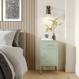 Metal side table locker in sage green with one drawer and one door, in a room next to a bed