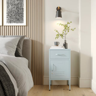 Metal side table locker in sky blue with one drawer and one door, in a room next to a bed