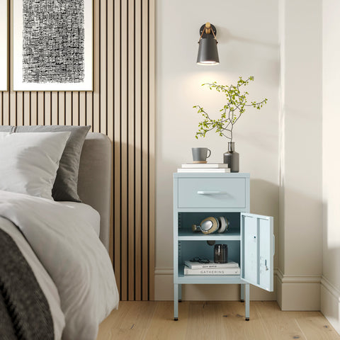 Metal side table locker in sky blue with one drawer and one door open showing books, in a room next to a bed