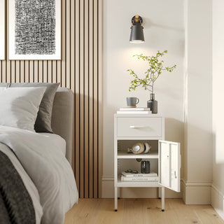 Metal side table locker in vanilla with one drawer and one door open showing books, in a room next to a bed