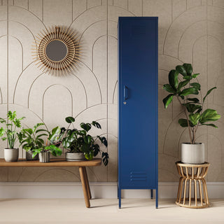 The Bexley single-door tall storage locker in navy blue, next to some plants